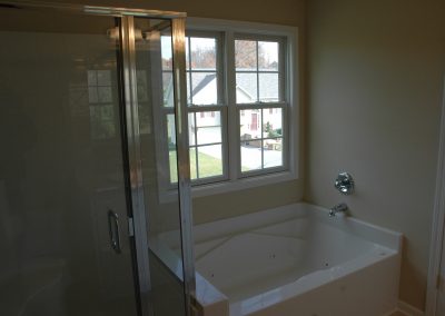 Bathdtub and glass-enclosed shower of a Davidson build plan house.